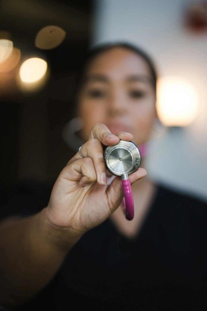 A woman holding up a stethoscope in front of her face.